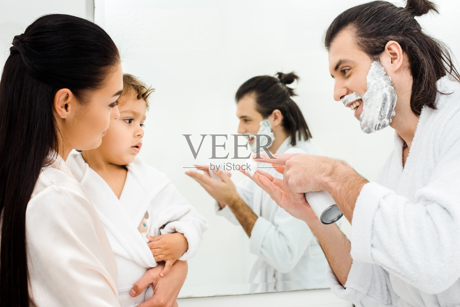 英俊男子向蹒跚学步的儿子展示剃须泡沫照片摄影图片