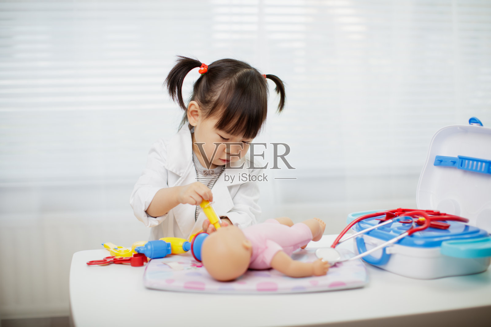 蹒跚学步的小女孩在家扮演医生照片摄影图片