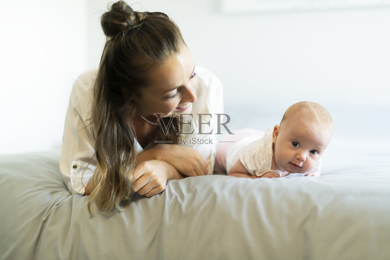 一个美丽的母亲和她2个月大的孩子在卧室的肖像照片摄影图片