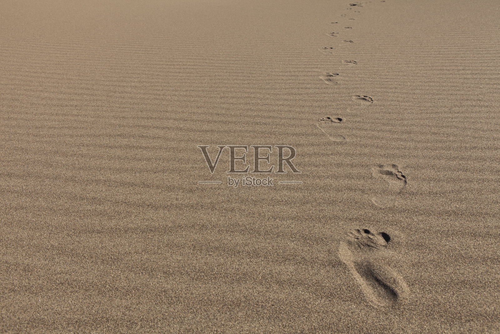 足迹穿过沙滩涟漪照片摄影图片