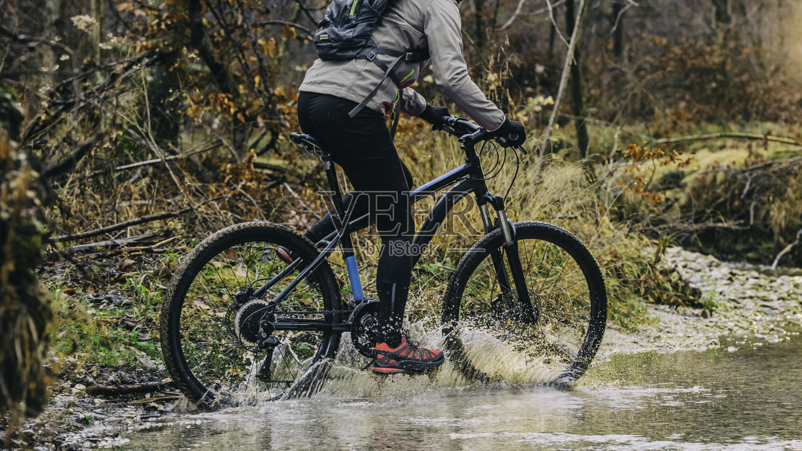 一个不知名的山地车手在森林里的水里骑车照片摄影图片