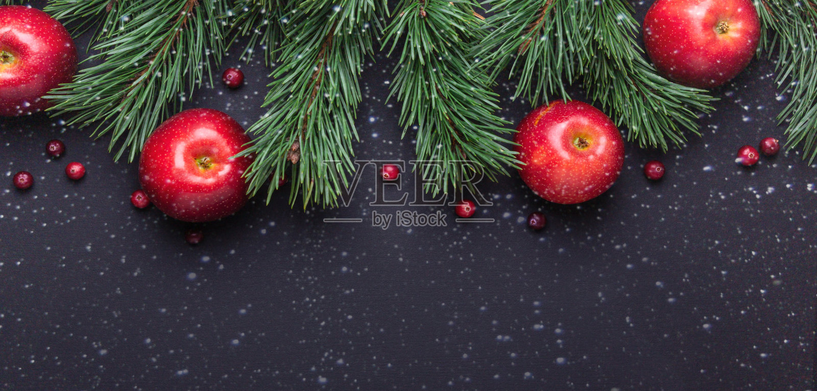 圣诞背景有树枝，红苹果和蔓越莓。黑暗的木桌上。降雪画效果照片摄影图片