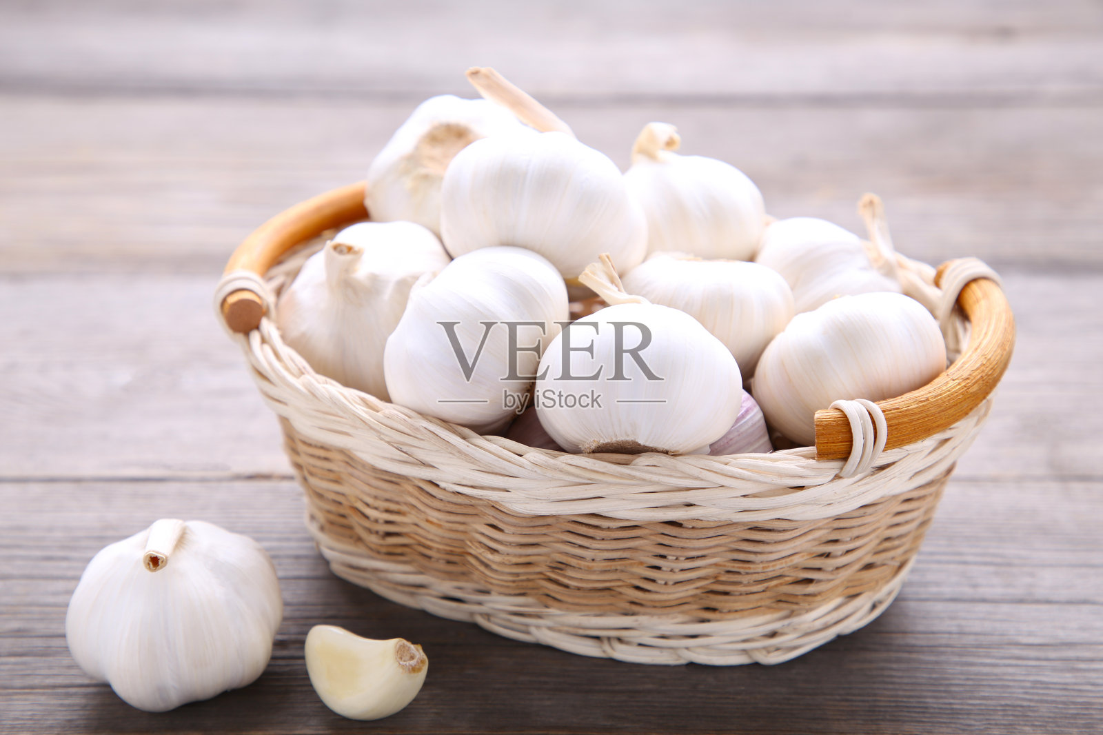 新鲜的大蒜在篮子里，在灰色的木制背景照片摄影图片