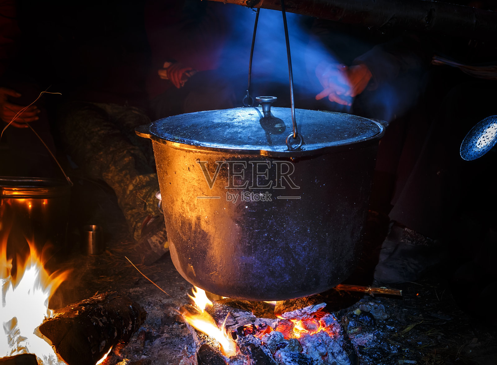 晚上在营火上抽着旅游水壶。春天的山脉。照片摄影图片