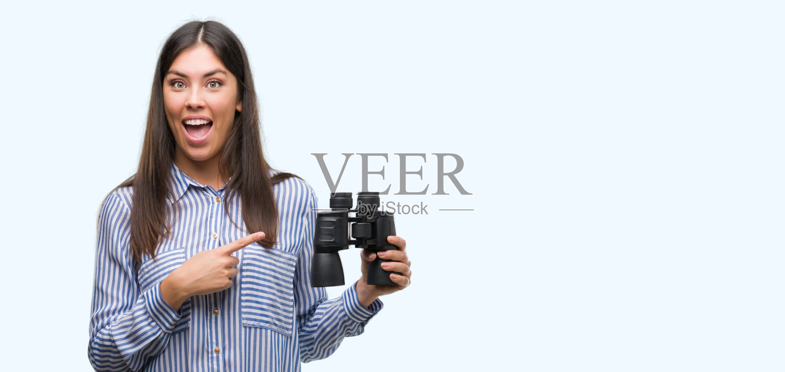 年轻的西班牙妇女拿着望远镜，很高兴地用手和手指指着照片摄影图片