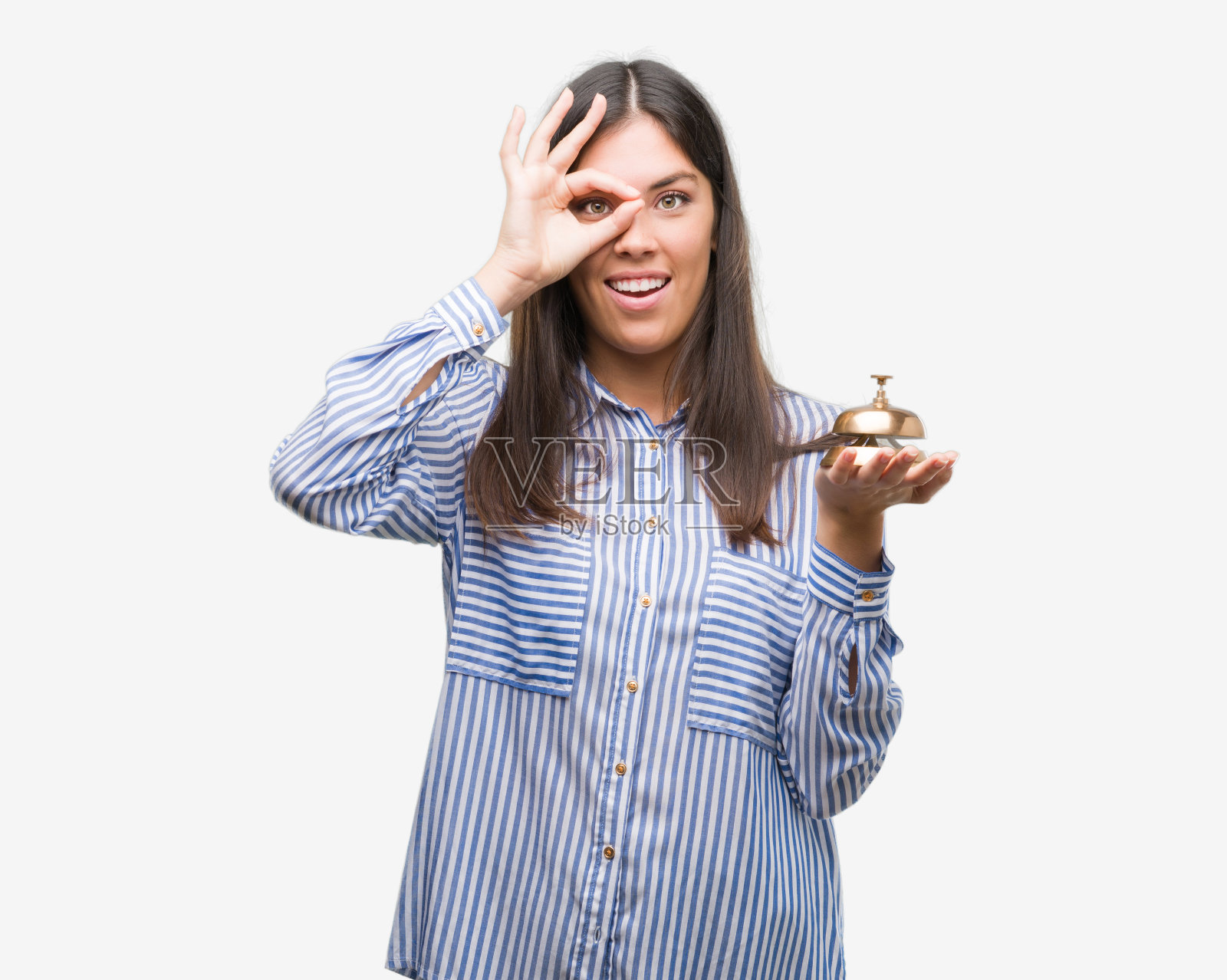 年轻美丽的西班牙人拿着酒店铃声与快乐的脸微笑做ok手势与手在眼睛透过手指照片摄影图片