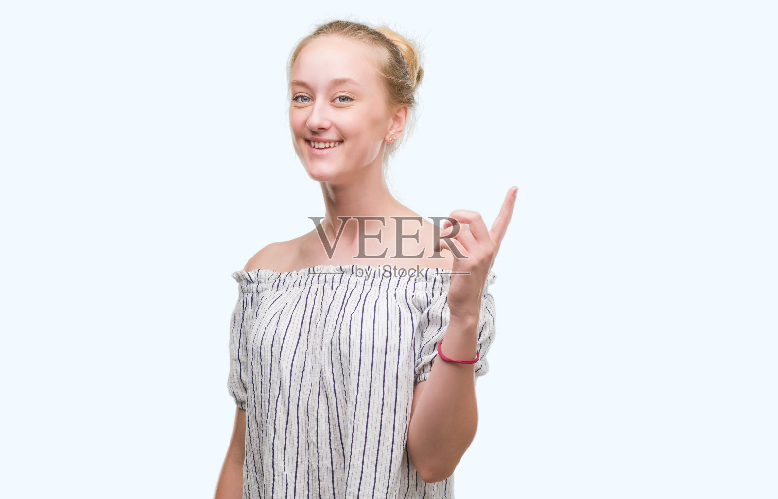 金发少女挽着发髻，惊讶地提出一个想法或问题，开心地指着手指，第一照片摄影图片