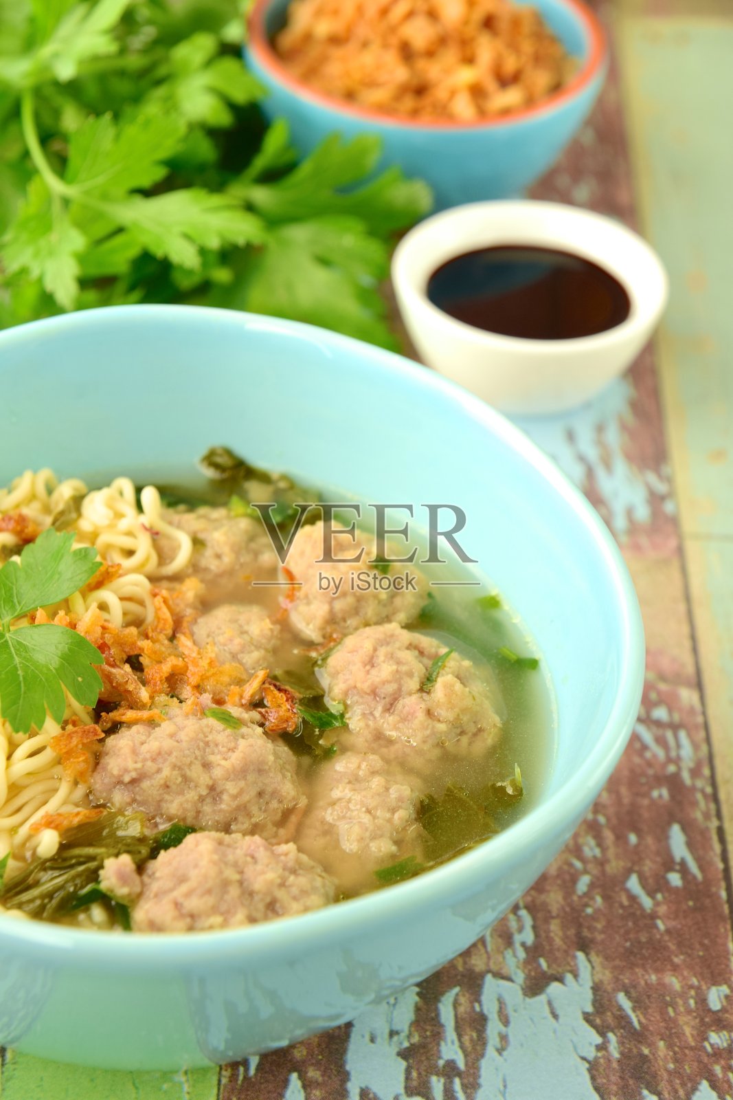 Bakso是印度尼西亚著名的传统街头小吃，肉丸配面条，配上香菜、酱油和炸葱照片摄影图片