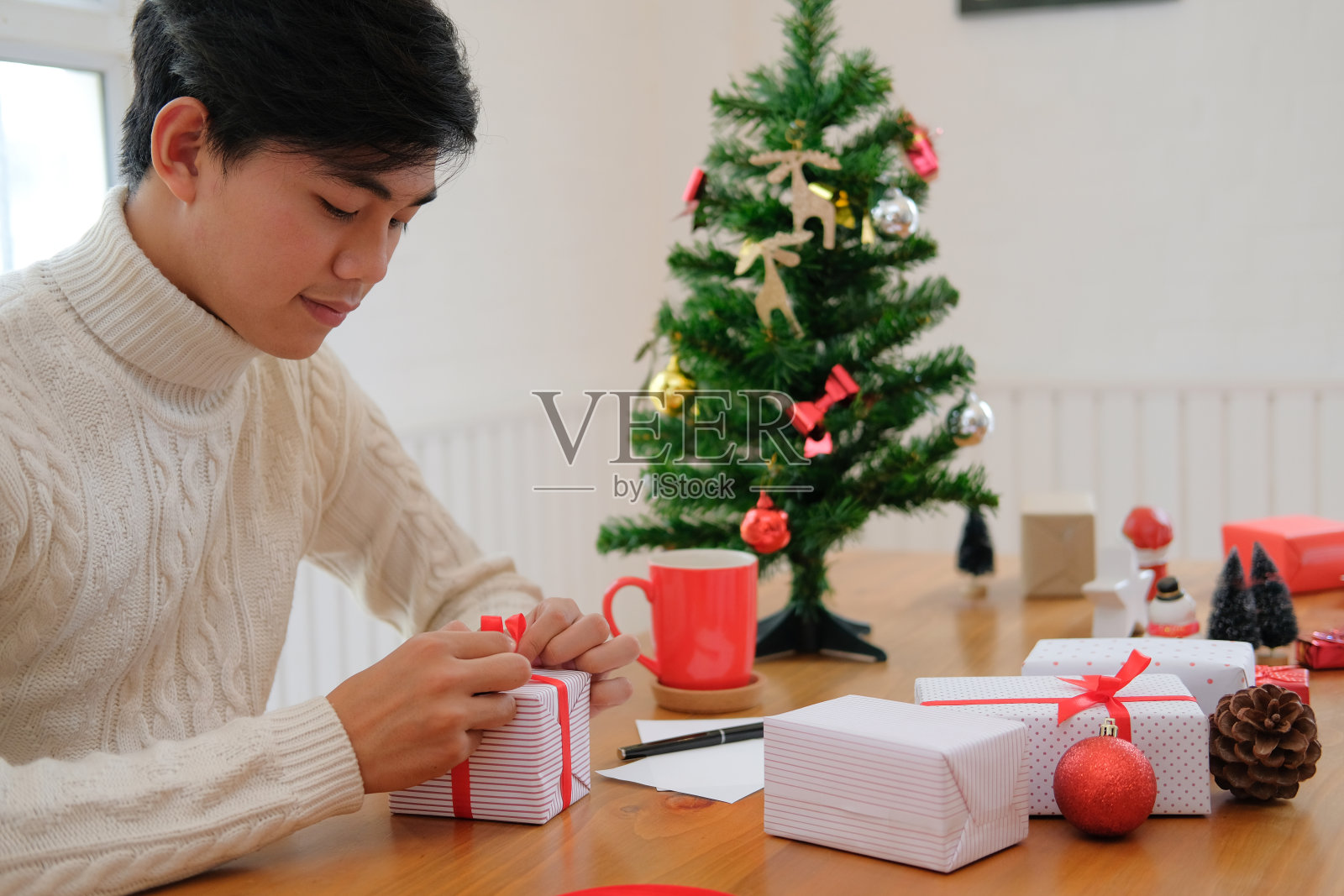 男人包装圣诞礼物礼物盒。庆祝圣诞节和新年。照片摄影图片