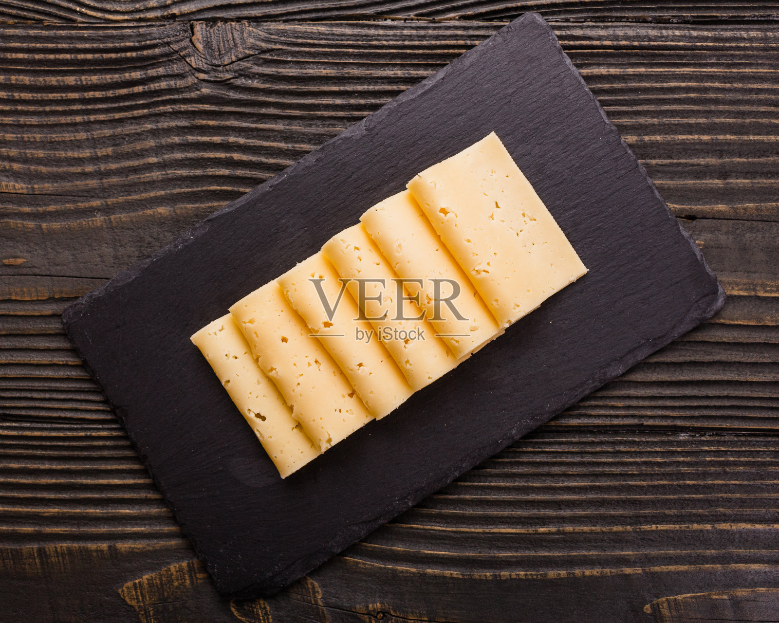 一片又一片的奶酪，放在木制的背景上照片摄影图片