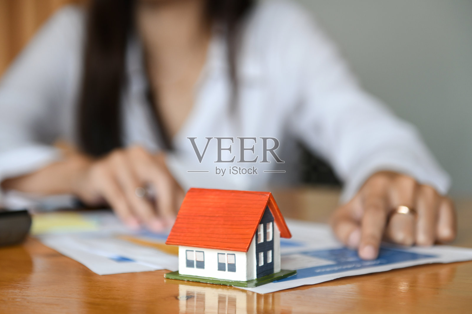 房屋销售经纪人正在谈判桌上工作。样板房在前台。照片摄影图片