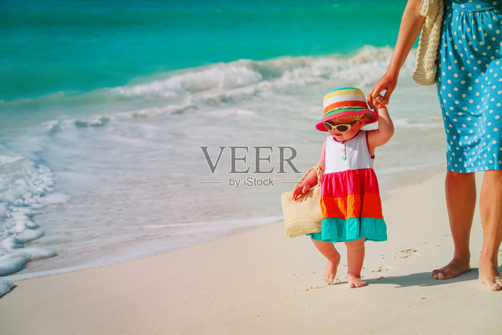妈妈和可爱的小女儿在海滩上散步照片摄影图片