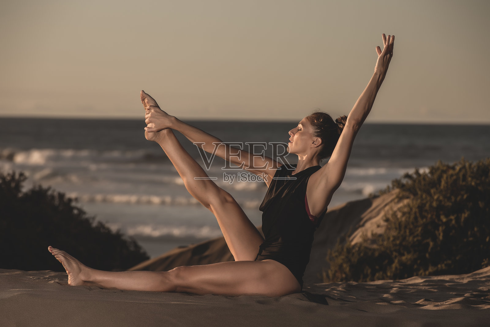 苗条的女人在海滩上练习瑜伽照片摄影图片