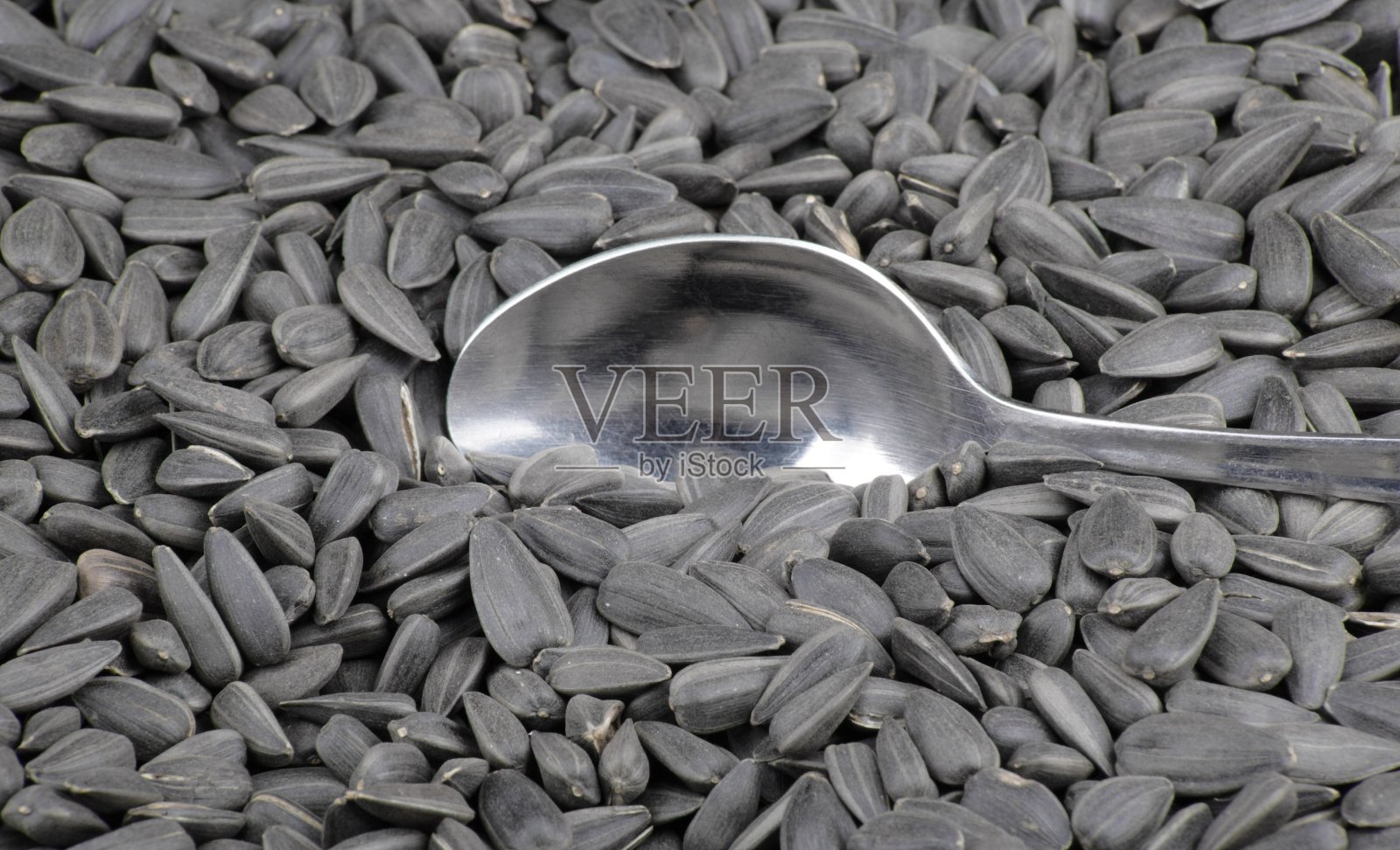 葵花籽背景和茶匙照片摄影图片