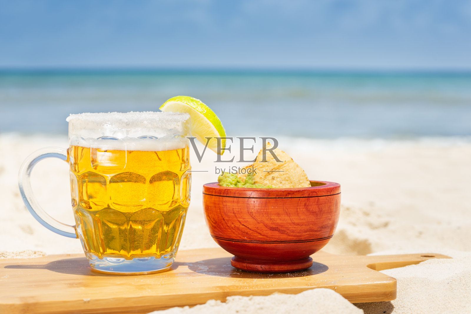 啤酒杯和海滩上的鳄梨色拉酱照片摄影图片