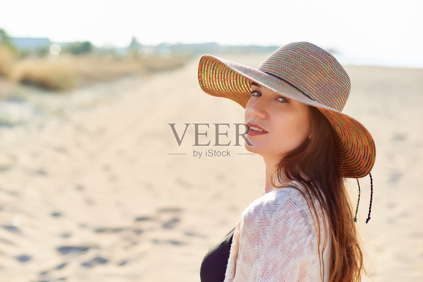 海滩上戴草帽的漂亮年轻女子照片摄影图片