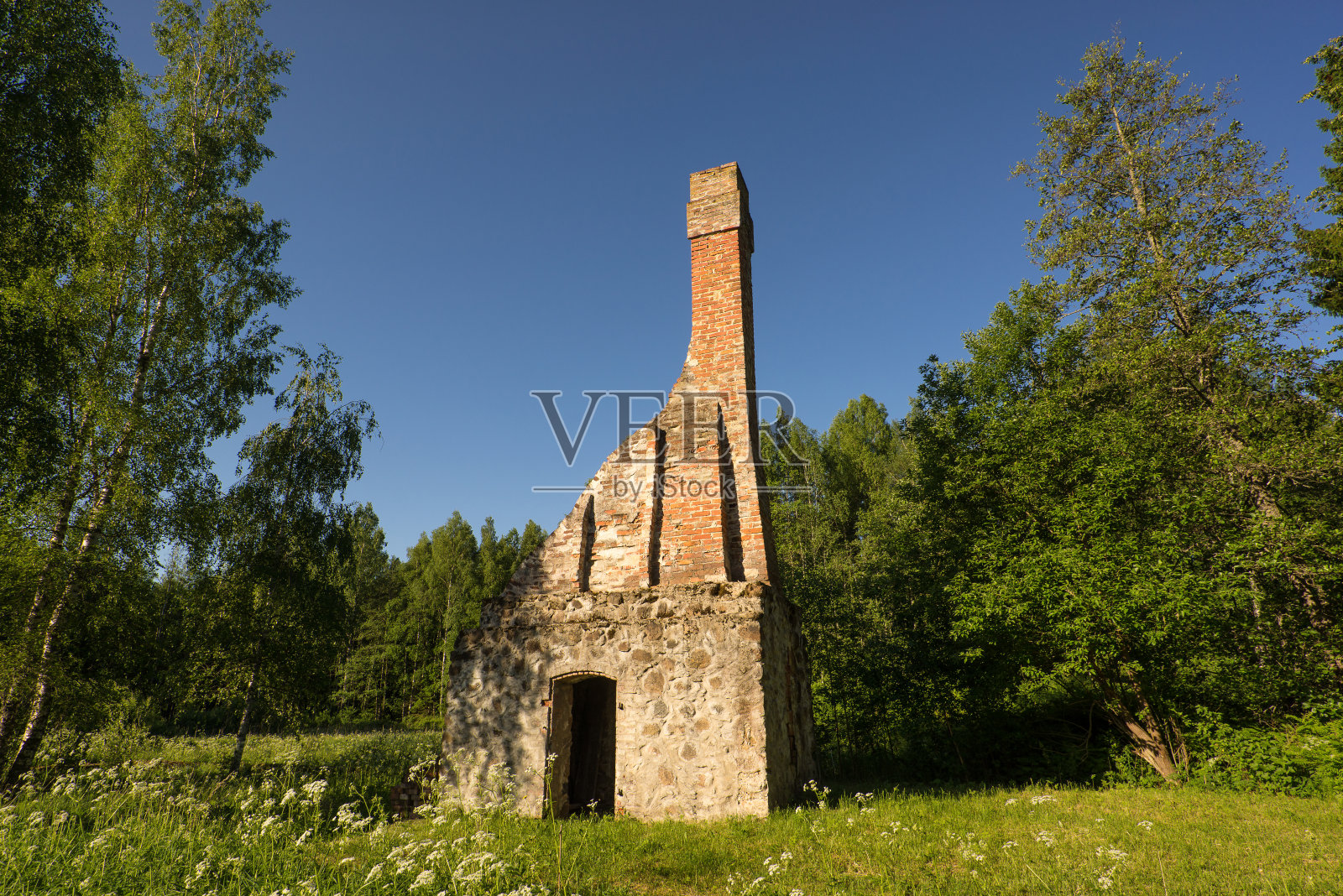 废弃的烤箱烟囱废墟。破碎的炉。绿色草甸环境，蓝天背景照片摄影图片