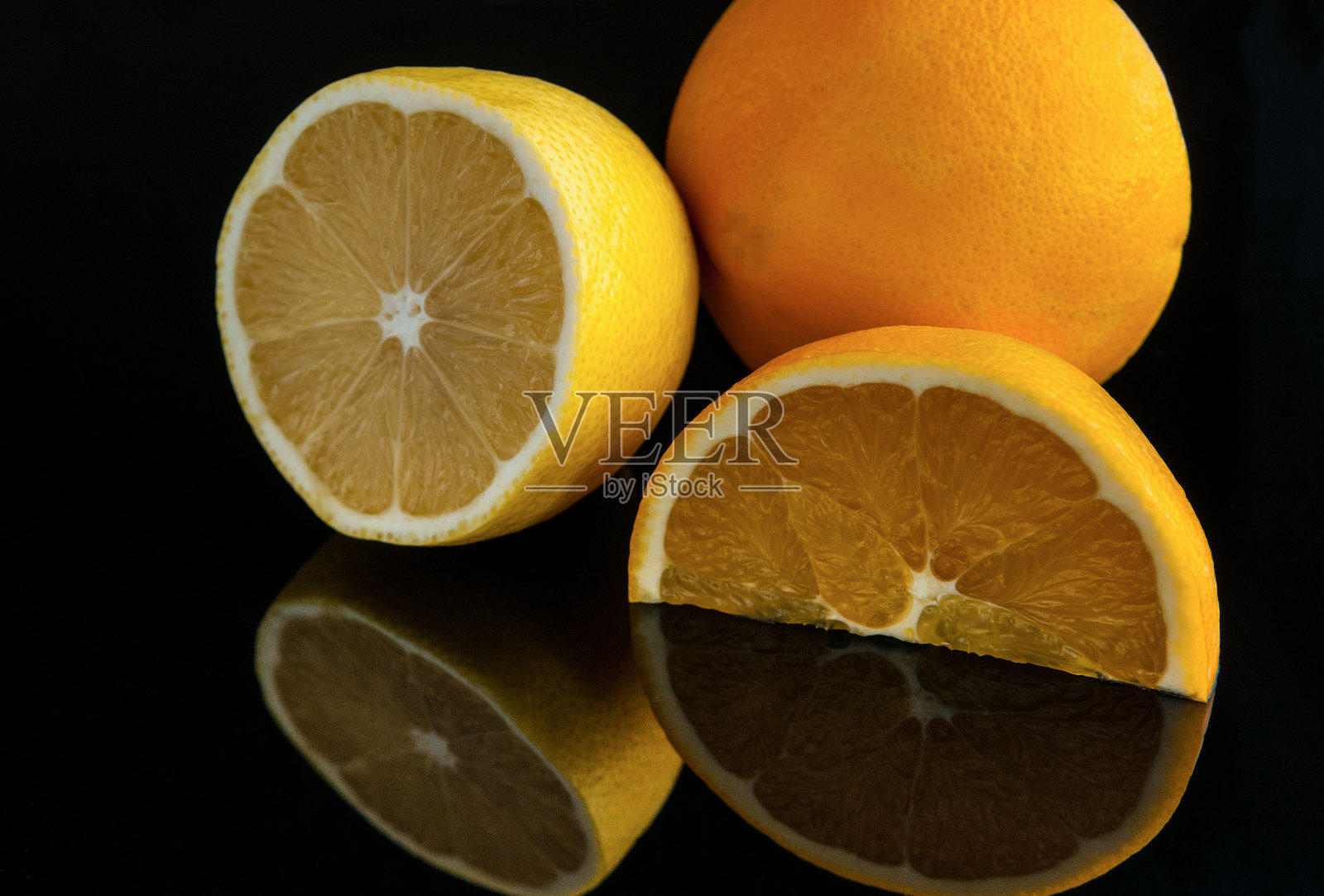 切柠檬和橙子在黑暗的背景反射。照片摄影图片