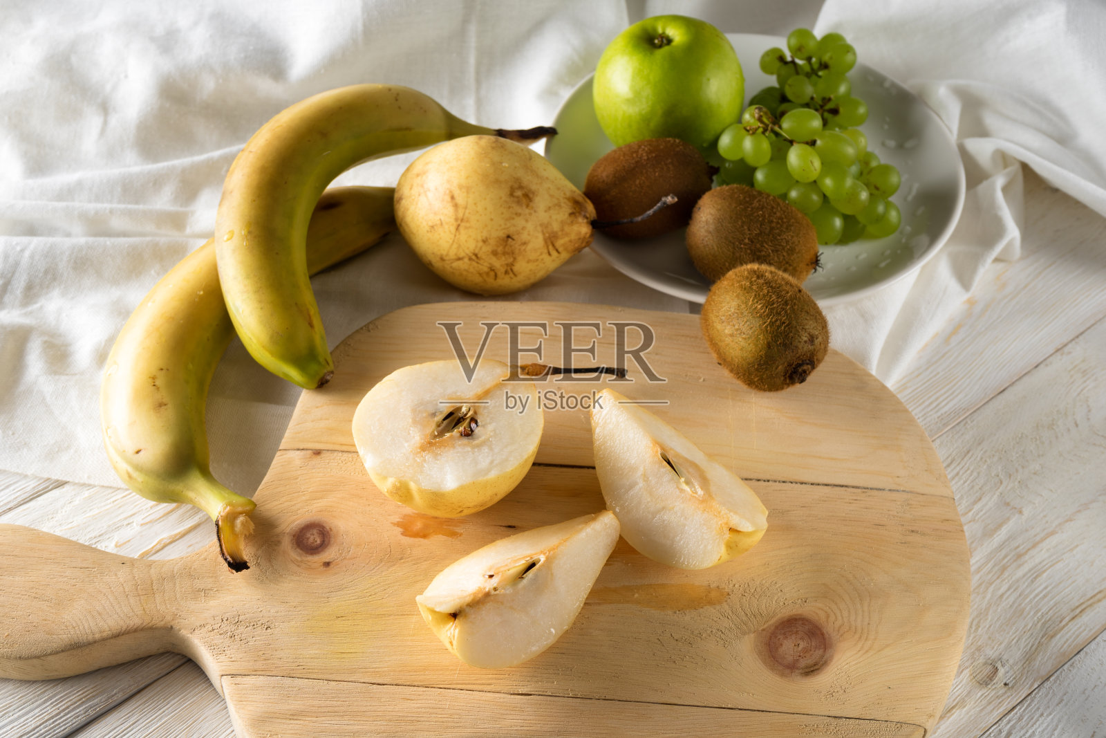 水果沙拉的配料。在砧板上切梨照片摄影图片