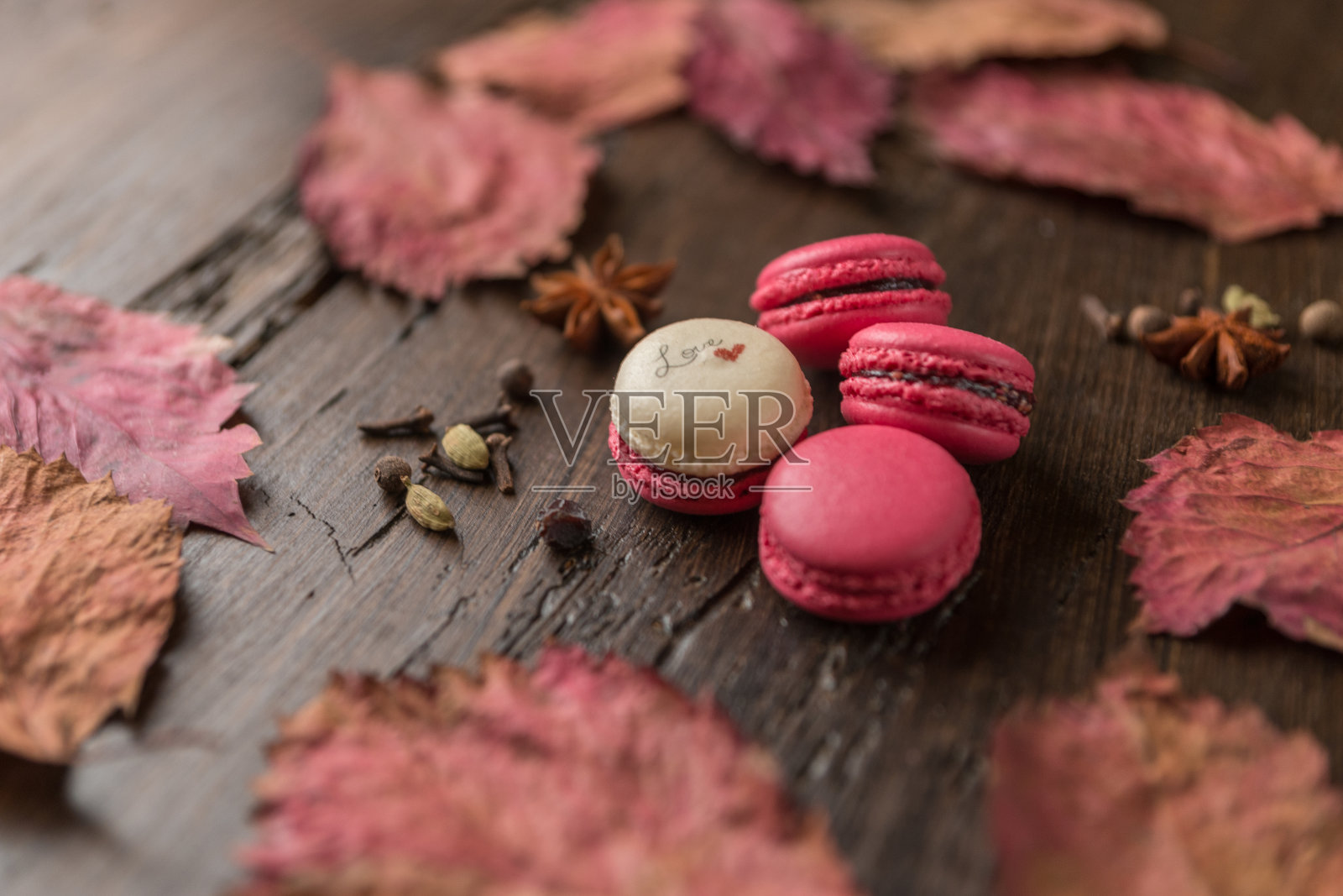 秋天的成分。粉色杏仁饼干，干树叶，深色木材背景。照片摄影图片