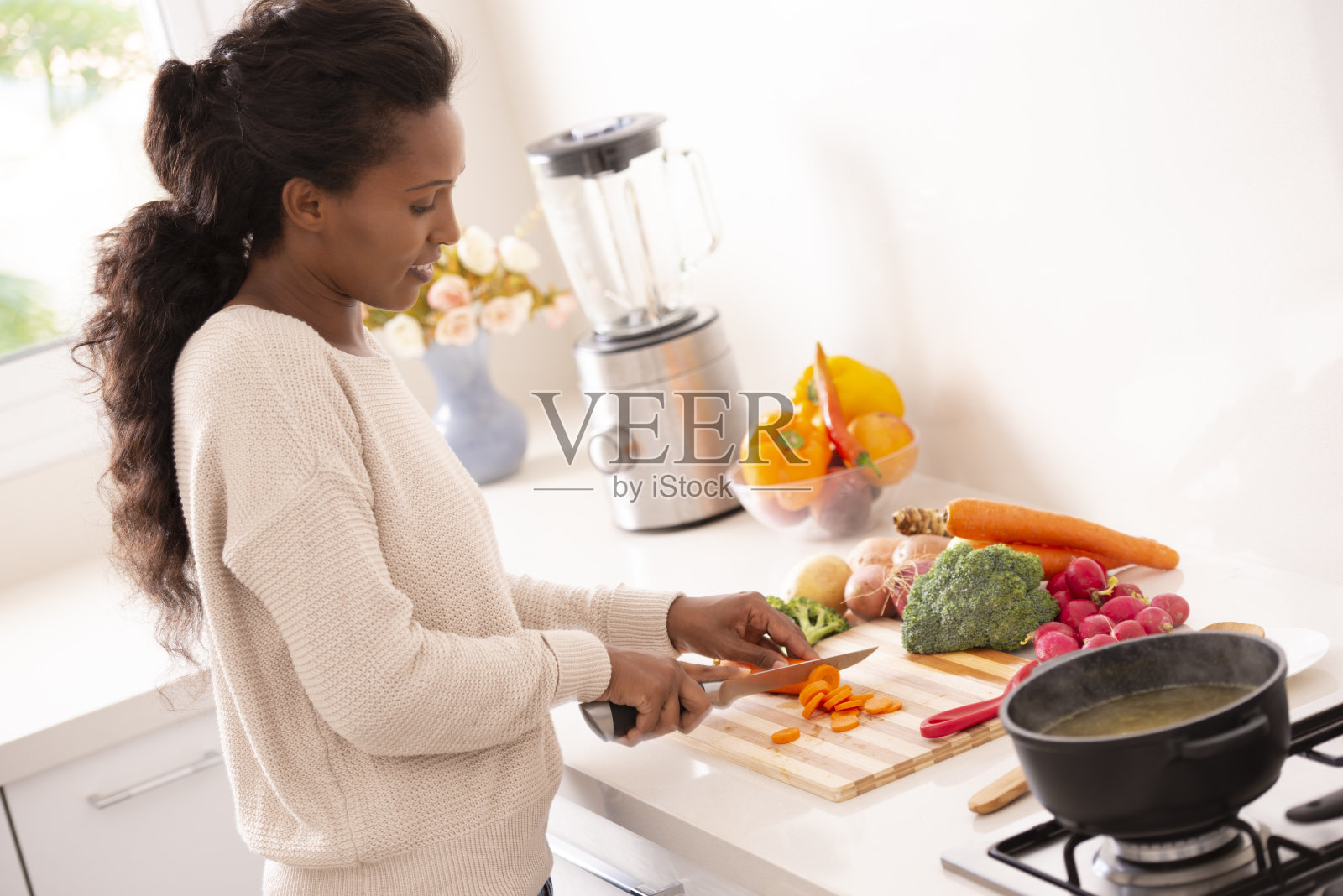女厨师在厨房切胡萝卜和其他蔬菜照片摄影图片