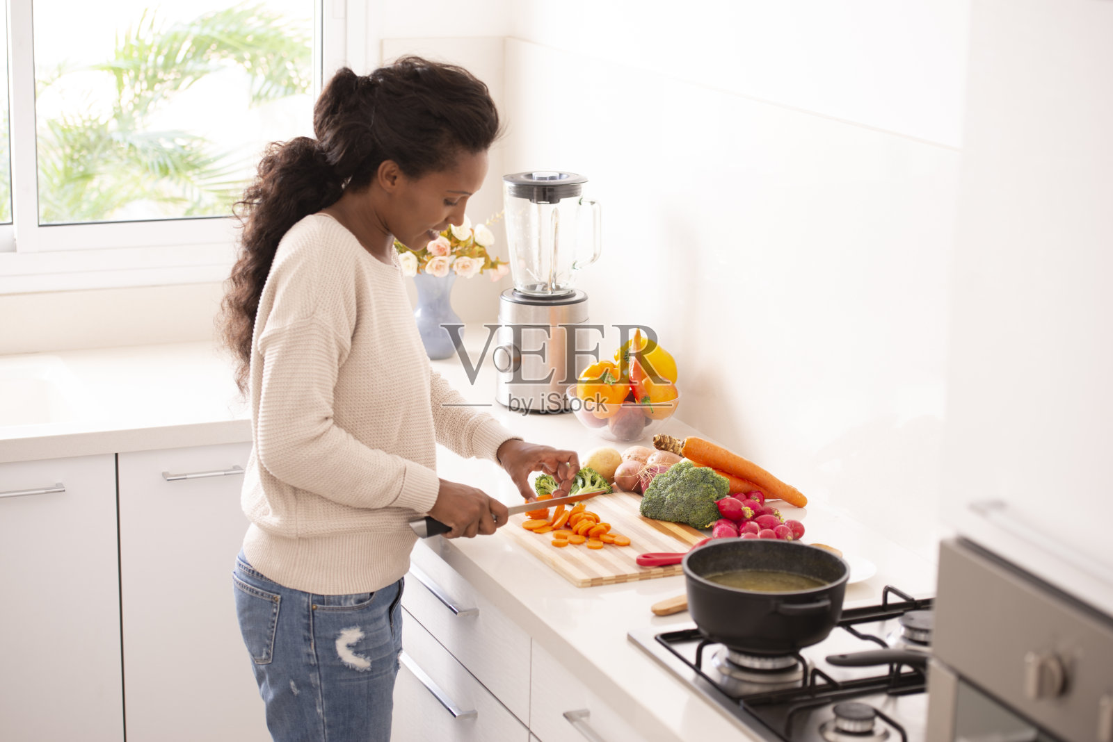 女厨师在厨房切胡萝卜和其他蔬菜照片摄影图片