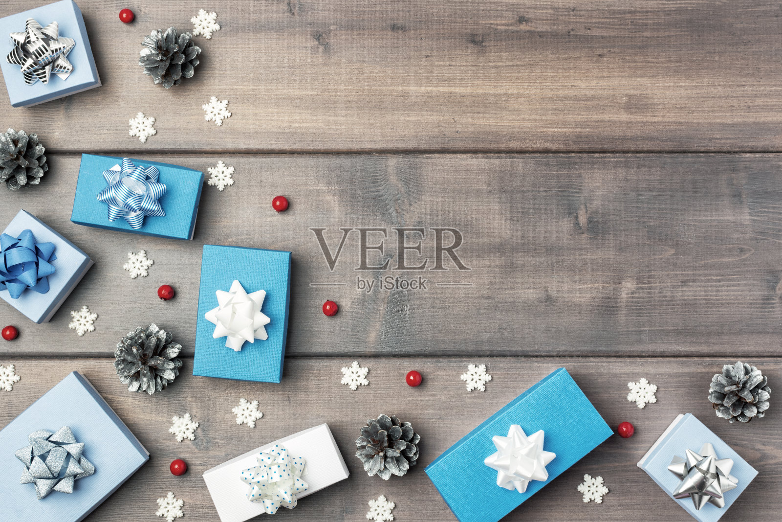 木质背景的角落里放着小礼品盒、圆锥形、红色浆果和装饰性雪花。圣诞作文与复制空间。节日布局与文字的地方。照片摄影图片