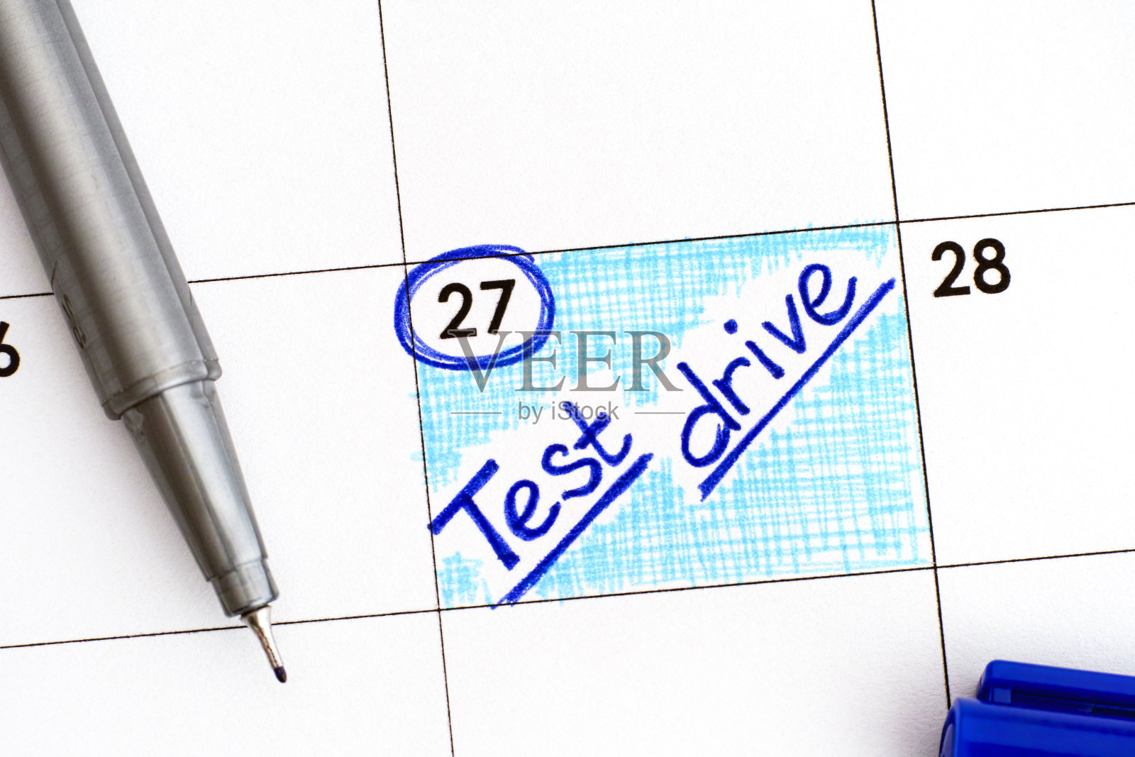 用蓝色笔在日历上提醒试驾。照片摄影图片