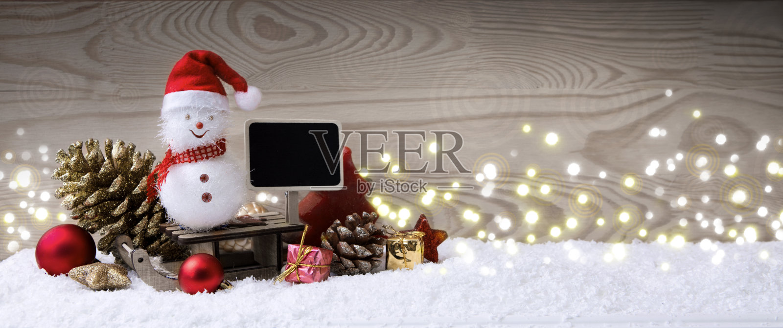 雪人和圣诞礼物在雪橇上孤立的木头背景。照片摄影图片