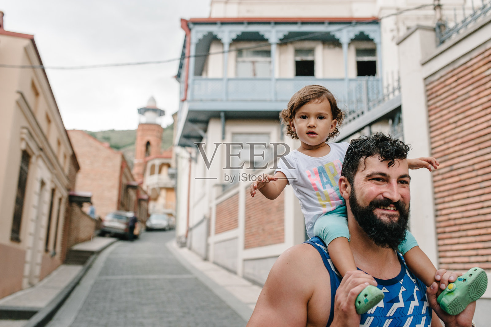 年轻的父亲在格鲁吉亚首都第比利斯与小女儿在户外街道上散步。照片摄影图片