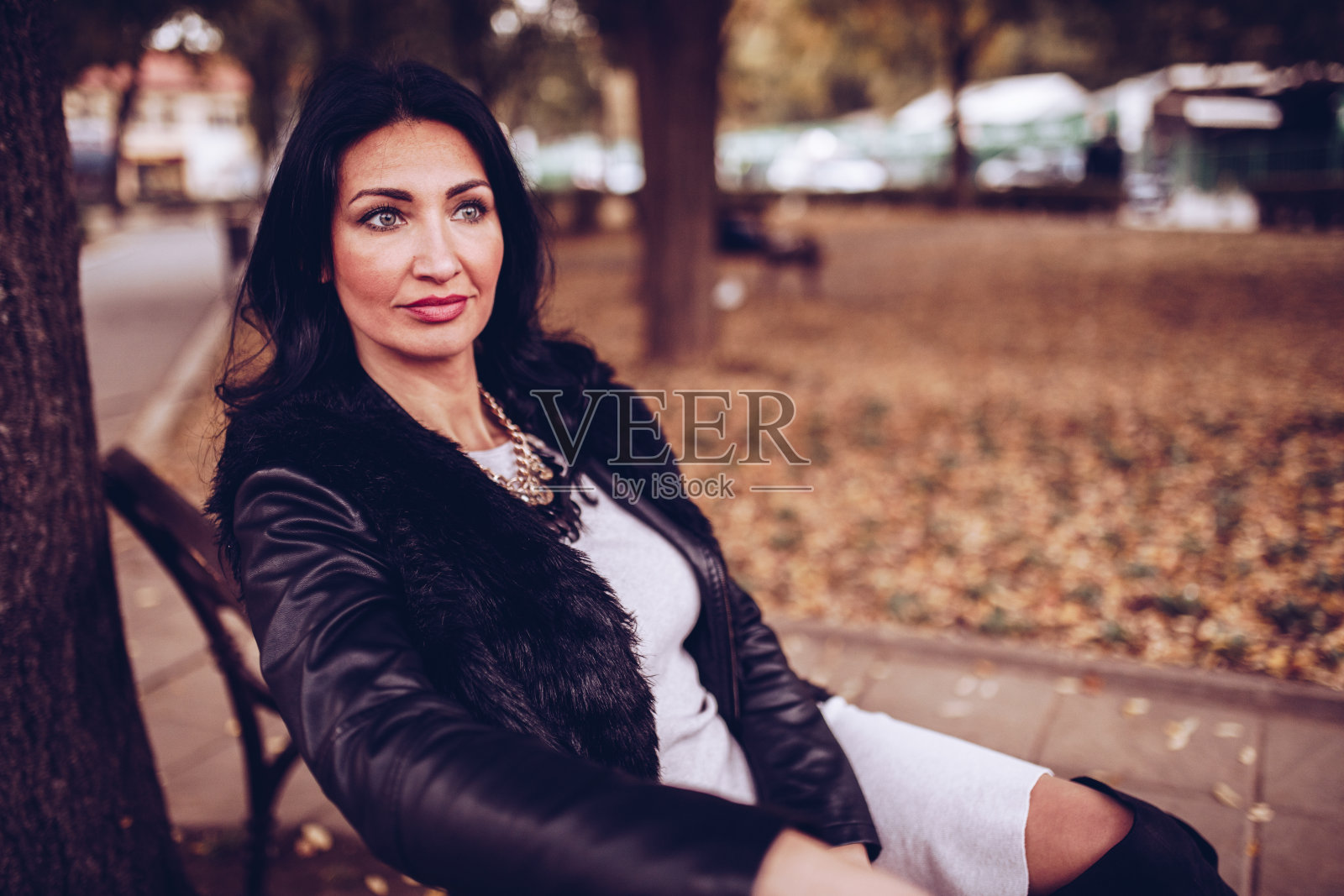 美丽优雅的女人坐在公园的长椅上，等待她的约会来的照片。照片摄影图片