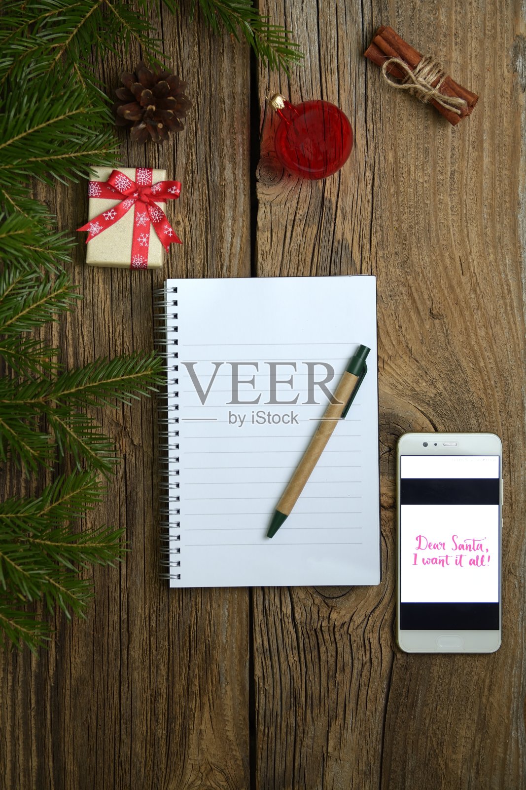 圣诞信以木制为背景，配有手机、礼品、杉木树枝、红色装饰品。圣诞和新年快乐作文。平躺，俯视图照片摄影图片