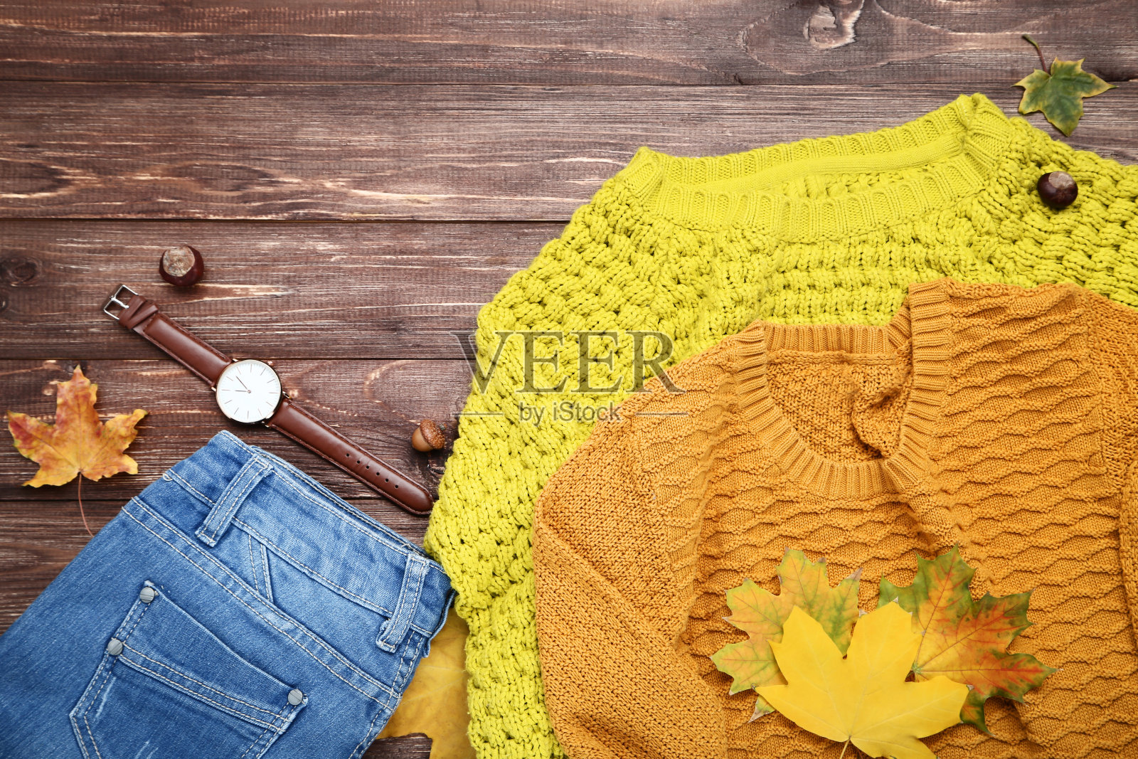 棕色的木桌上放着针织毛衣和枫叶照片摄影图片