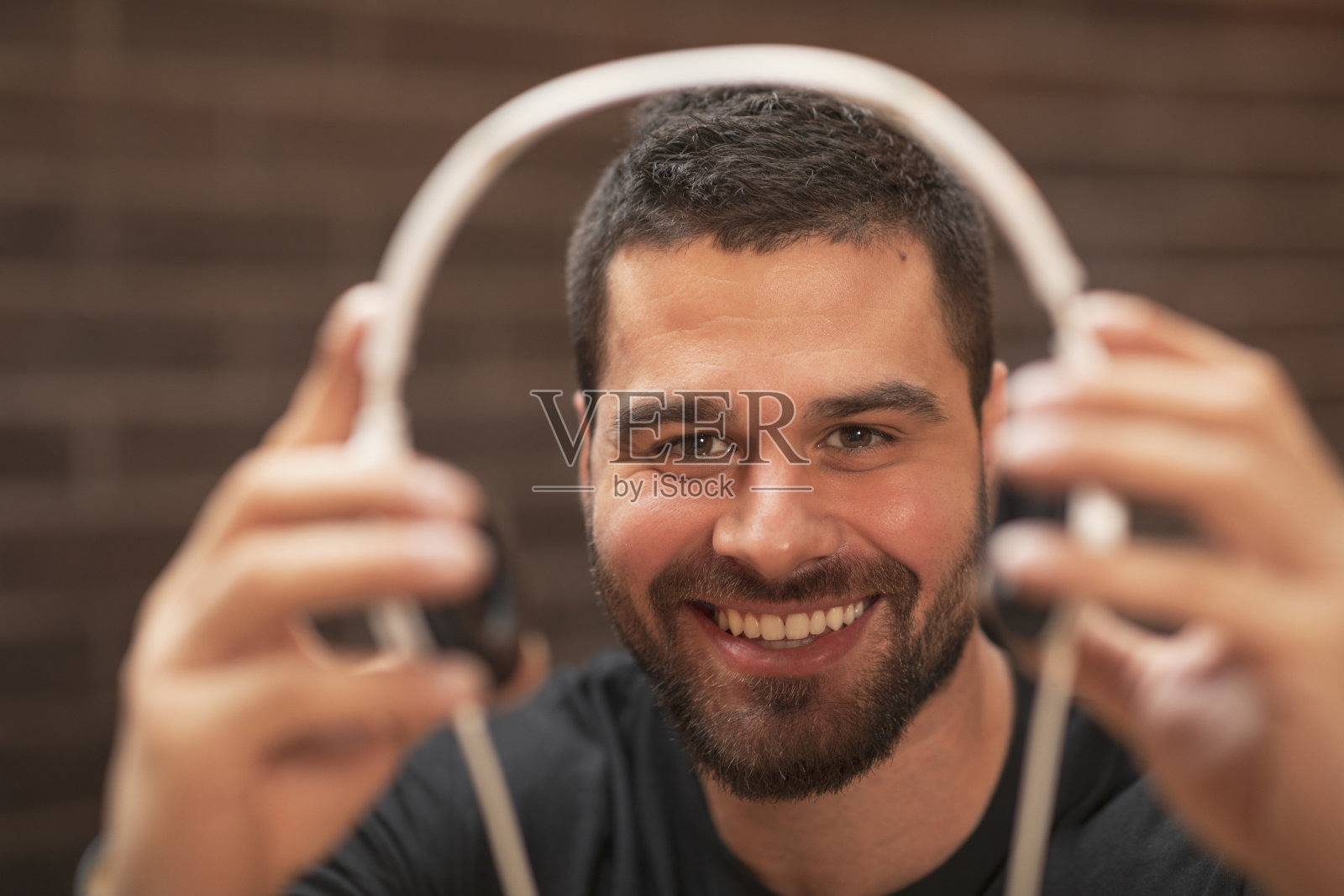 留着胡子的帅气男子戴着耳机，在咖啡馆餐厅的咖啡休息时间听音乐。照片摄影图片