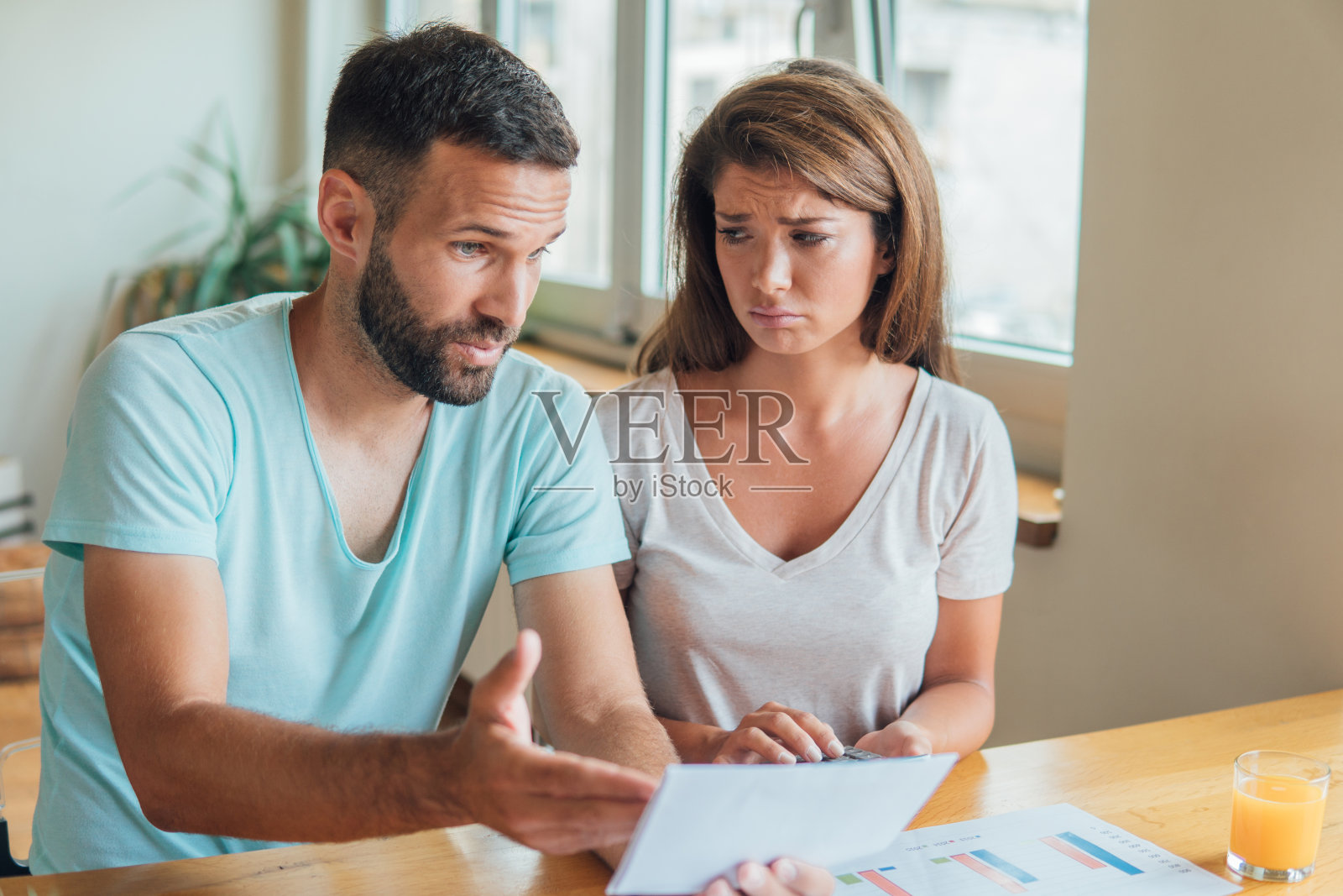 悲伤的女人看着愤怒的男人拿着金融账单照片摄影图片