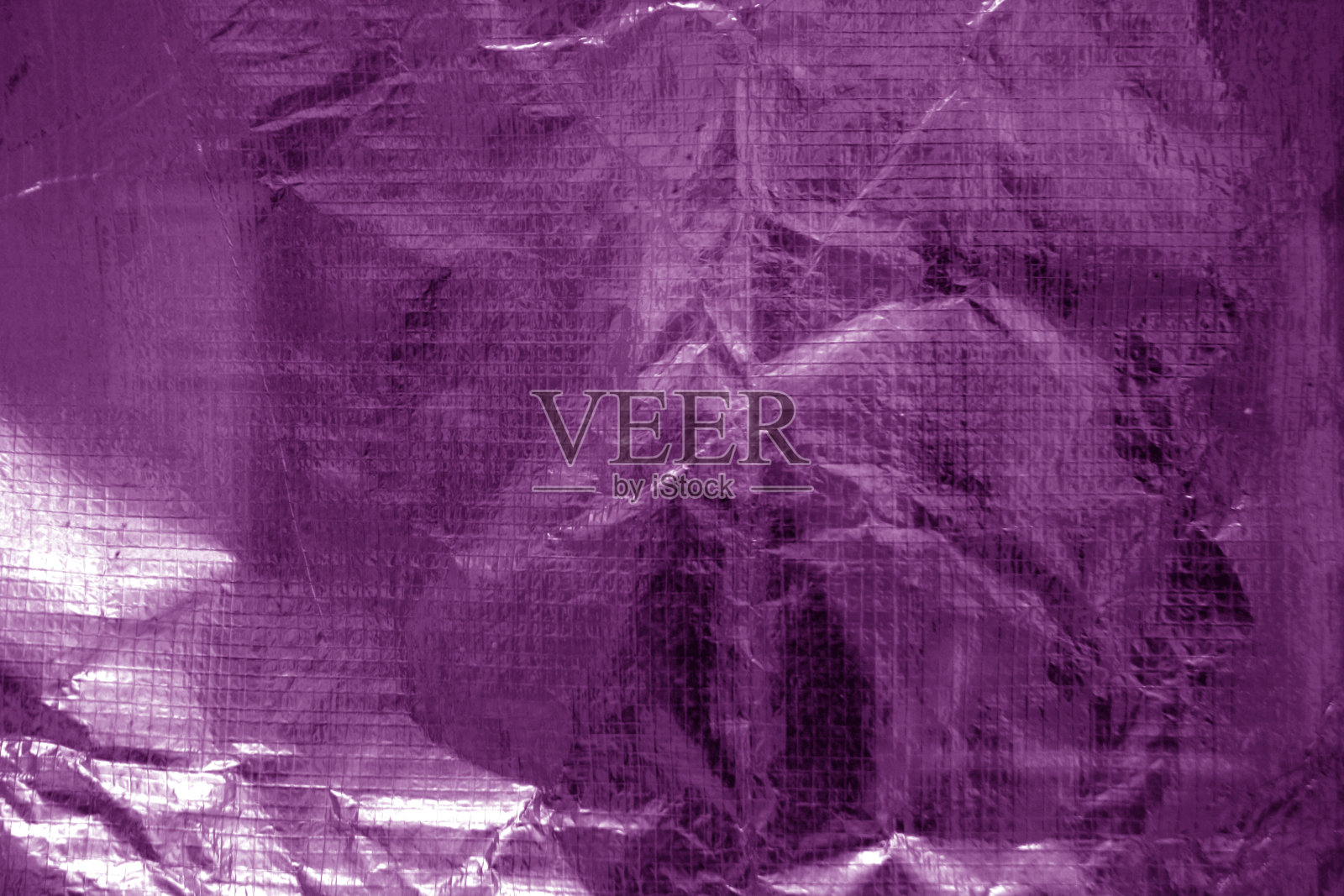 被揉皱的透明塑料表面呈紫色。照片摄影图片