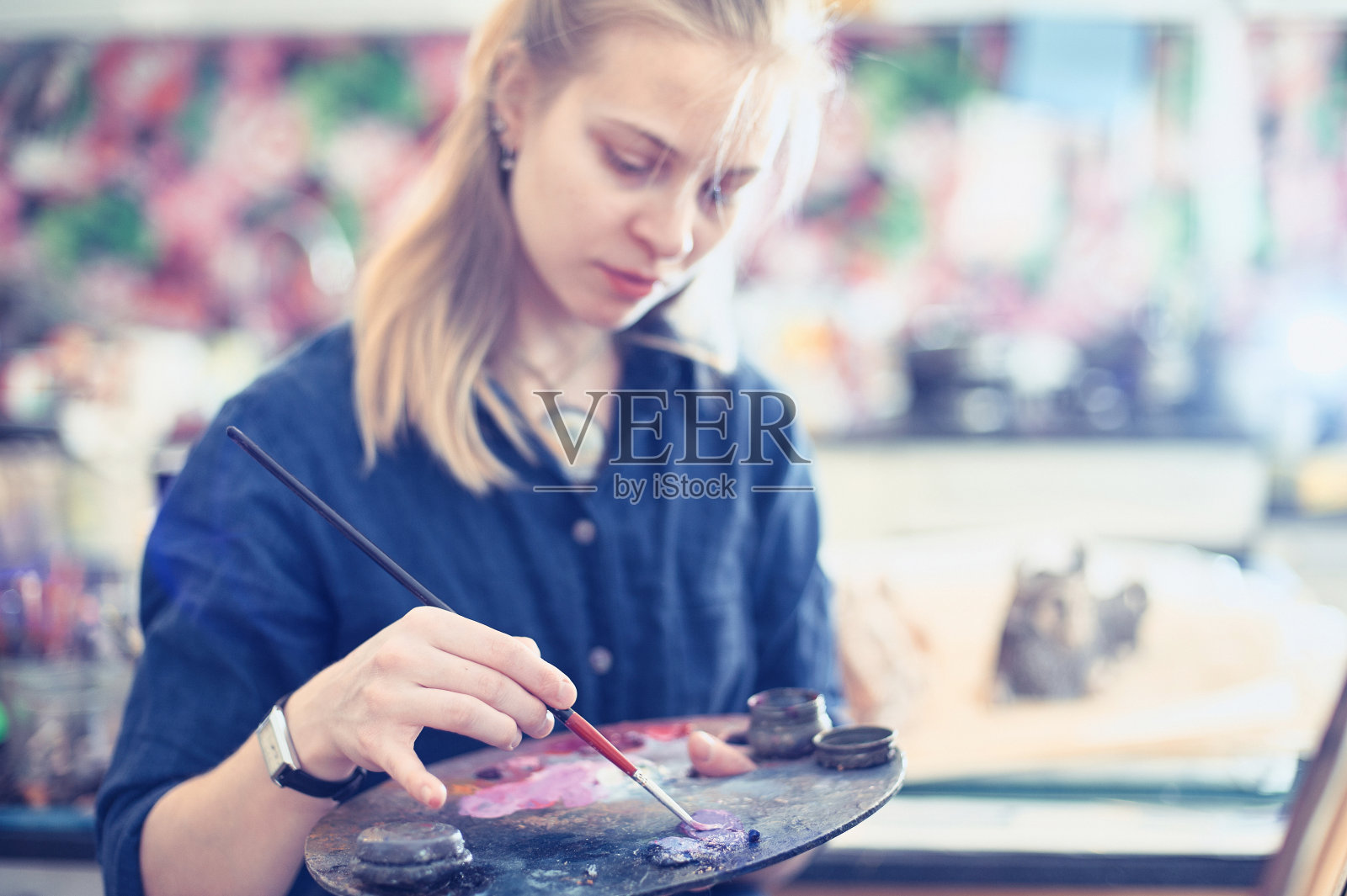 年轻的女艺术家在画室里作画。选择性聚焦前景。照片摄影图片