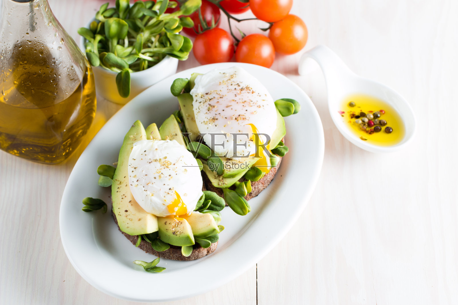牛油果吐司，樱桃番茄木背景。早餐配牛油果吐司，素食，健康饮食理念。健康的牛油果和水煮鸡蛋三明治。照片摄影图片