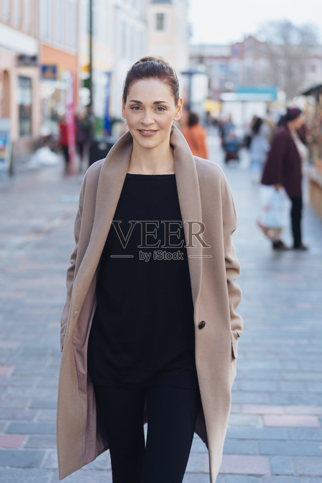 年轻的女人穿着大衣走在街上照片摄影图片