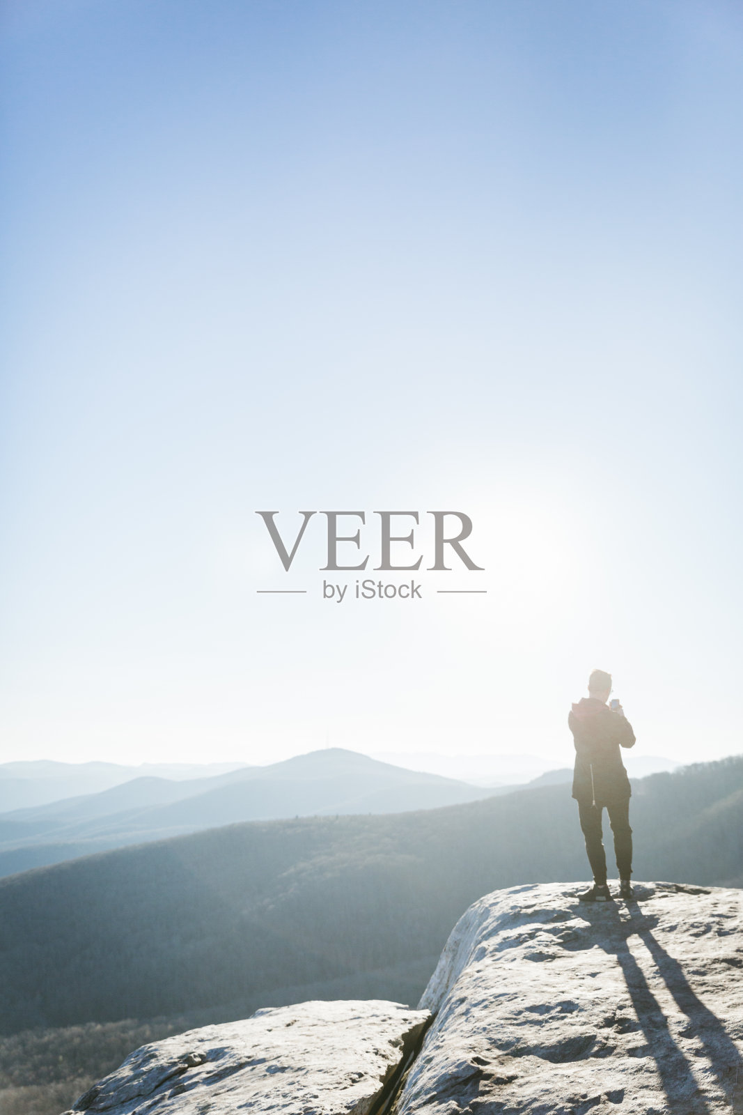 一名男子坐在蓝岭公园路上的一块岩石上用手机照片摄影图片