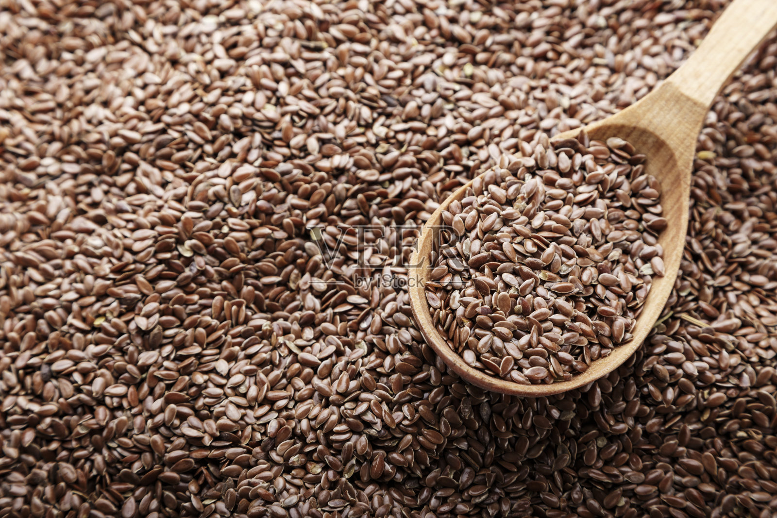 把亚麻籽撒在勺子里作为背景。照片摄影图片