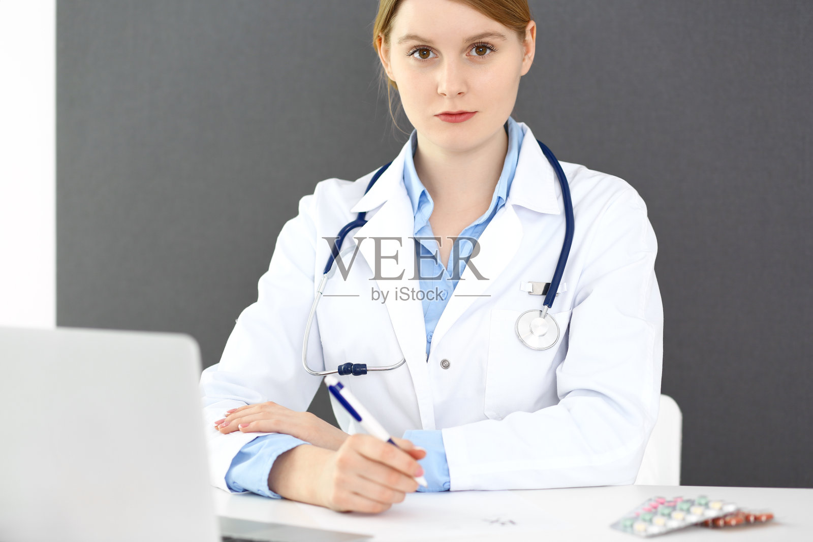 女医生坐在诊所或医院靠窗处填写处方或病历表格。医疗保健理念。医生在工作中照片摄影图片