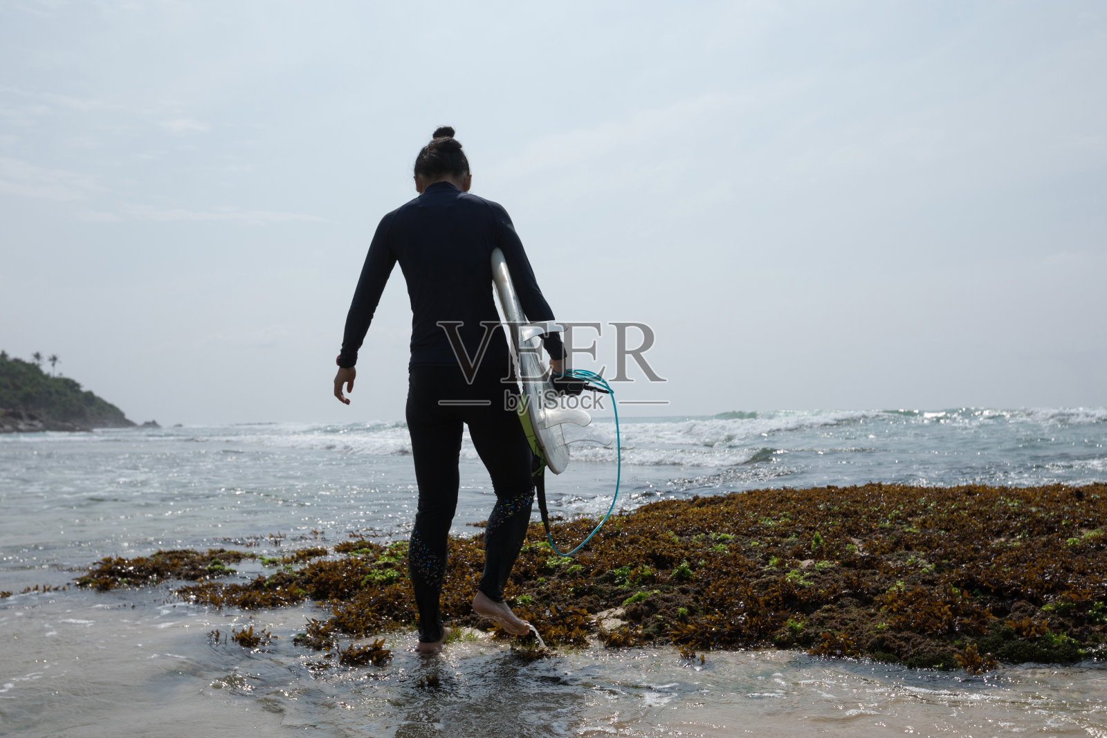 妇女冲浪者与冲浪板行走在海边珊瑚礁照片摄影图片