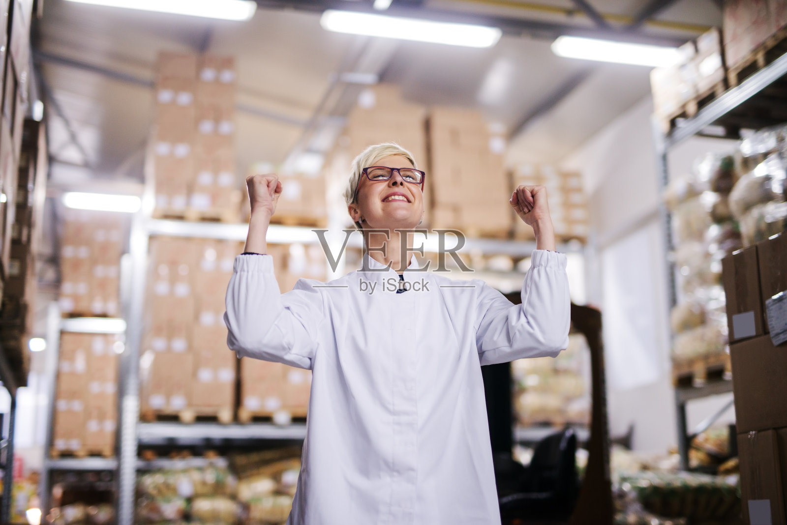 快乐的女工庆祝成功。仓库内部。照片摄影图片