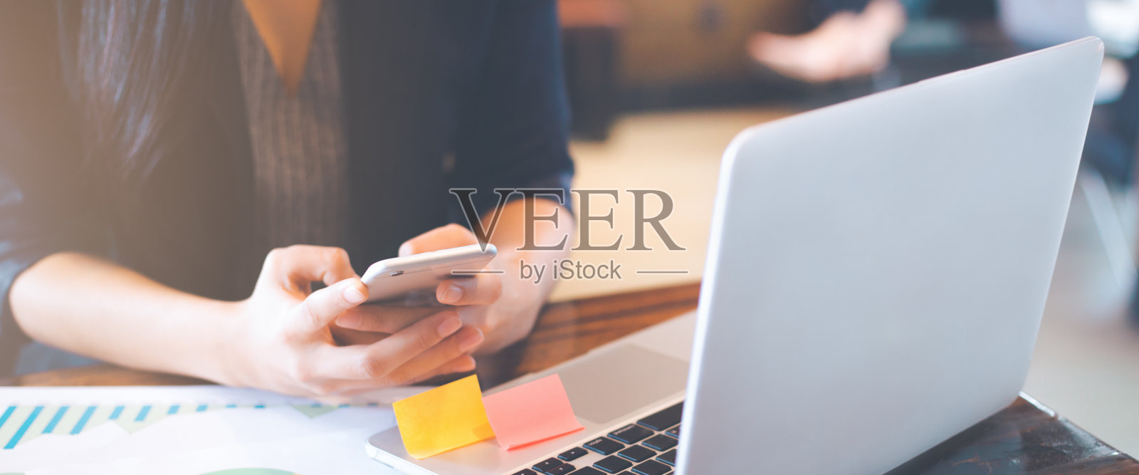 商务女性在办公室使用智能手机和笔记本电脑。照片摄影图片