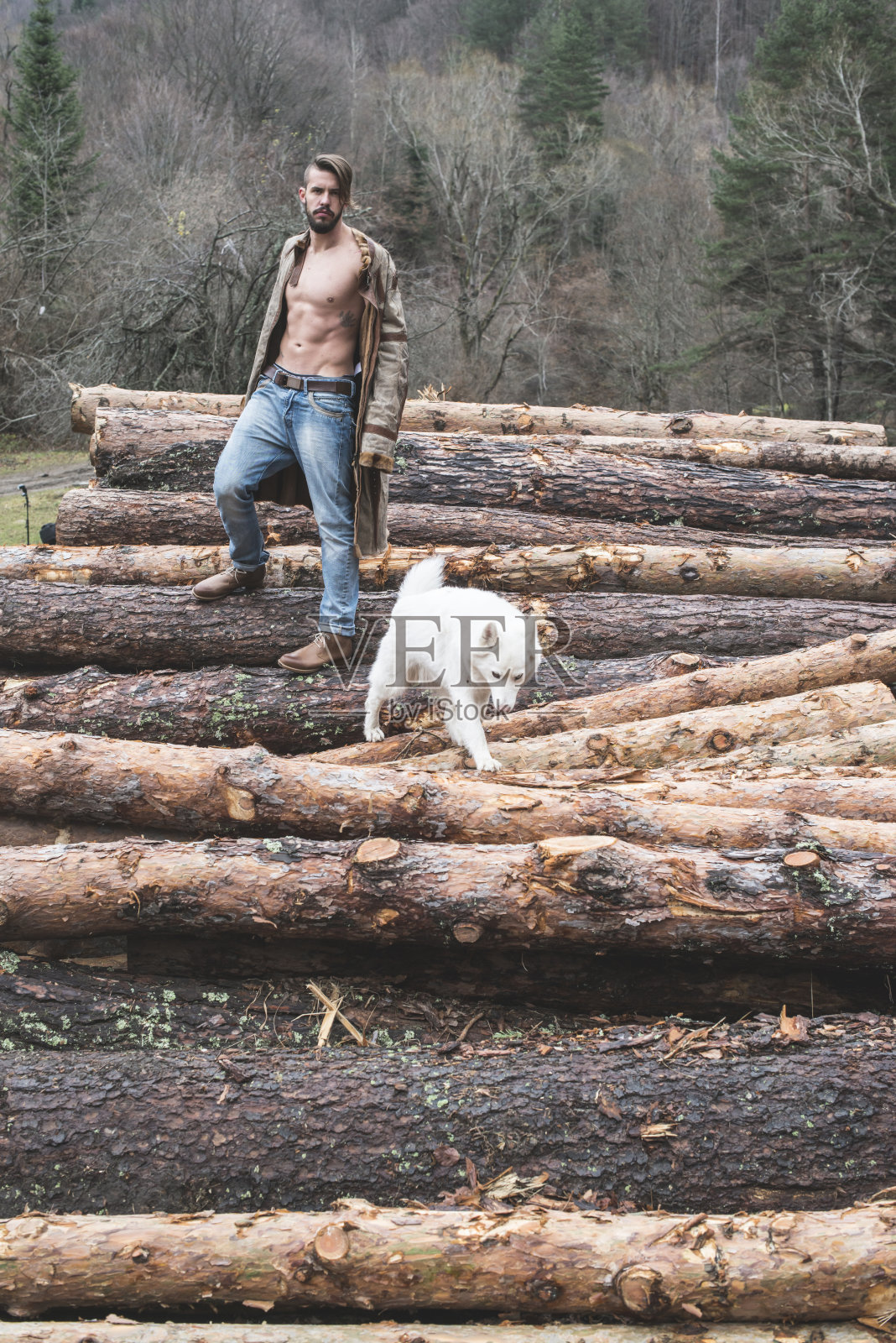 年轻人和狗在森林里的原木上照片摄影图片