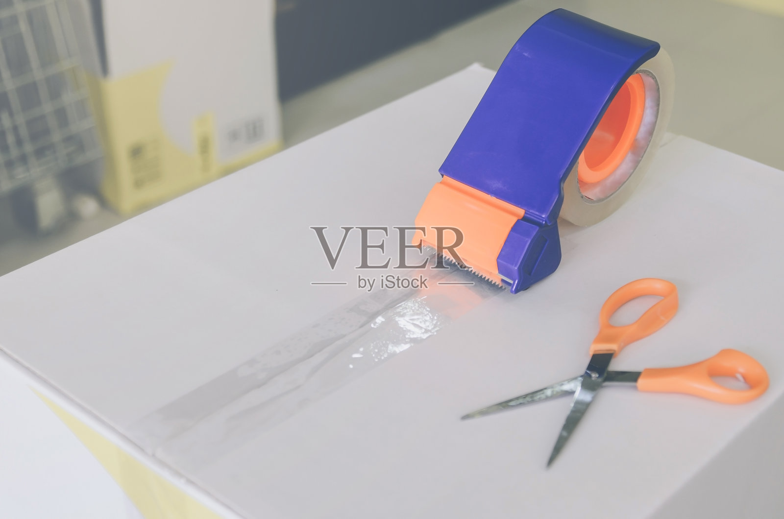 用剪刀和透明胶带剪准备待运的包裹。照片摄影图片