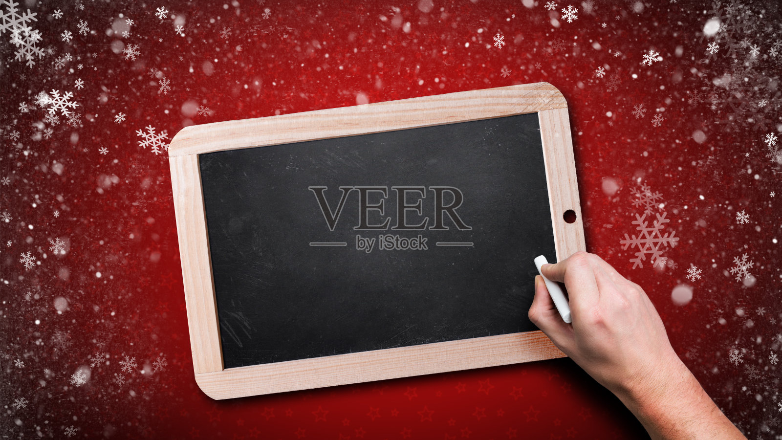 在飘落的雪花中，手开始在空黑板上写字照片摄影图片