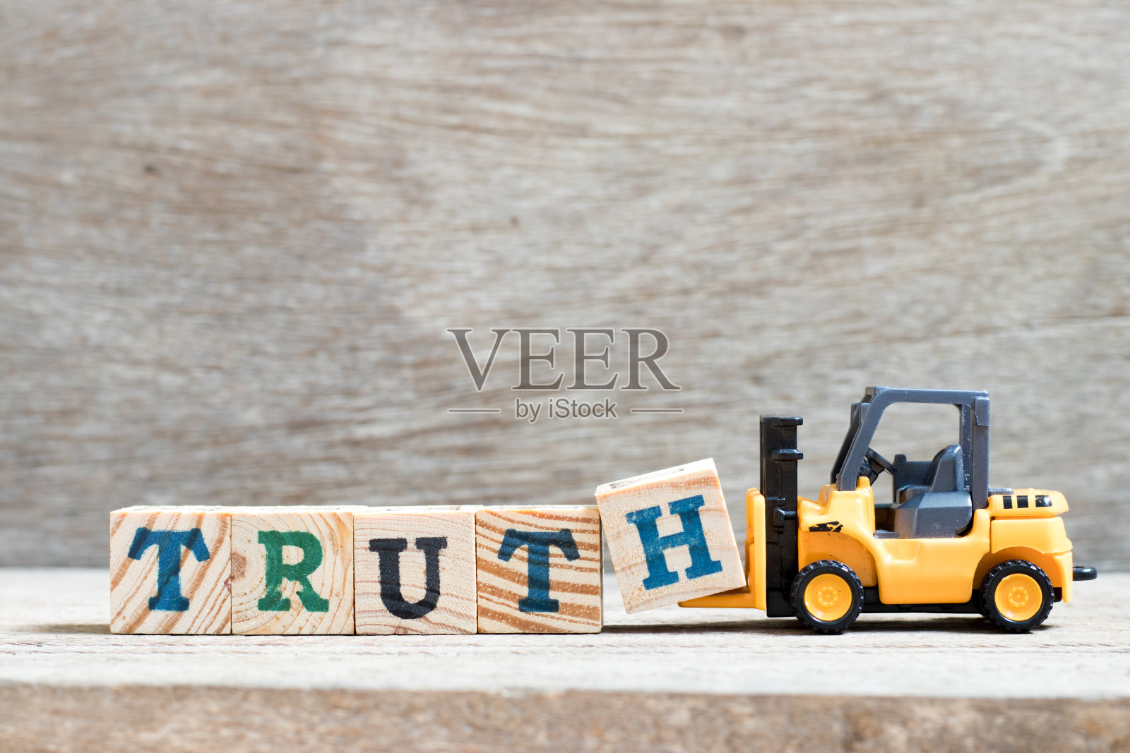 玩具铲车持字母块h，以完成字真木为背景照片摄影图片