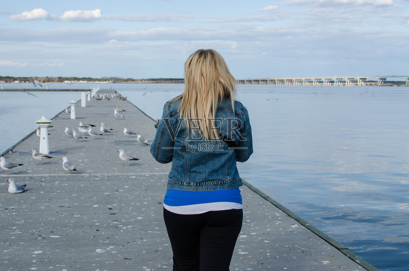 一个阳光明媚的春日，年轻的成年女子走到马里兰州剑桥市Choptank河附近的码头上照片摄影图片
